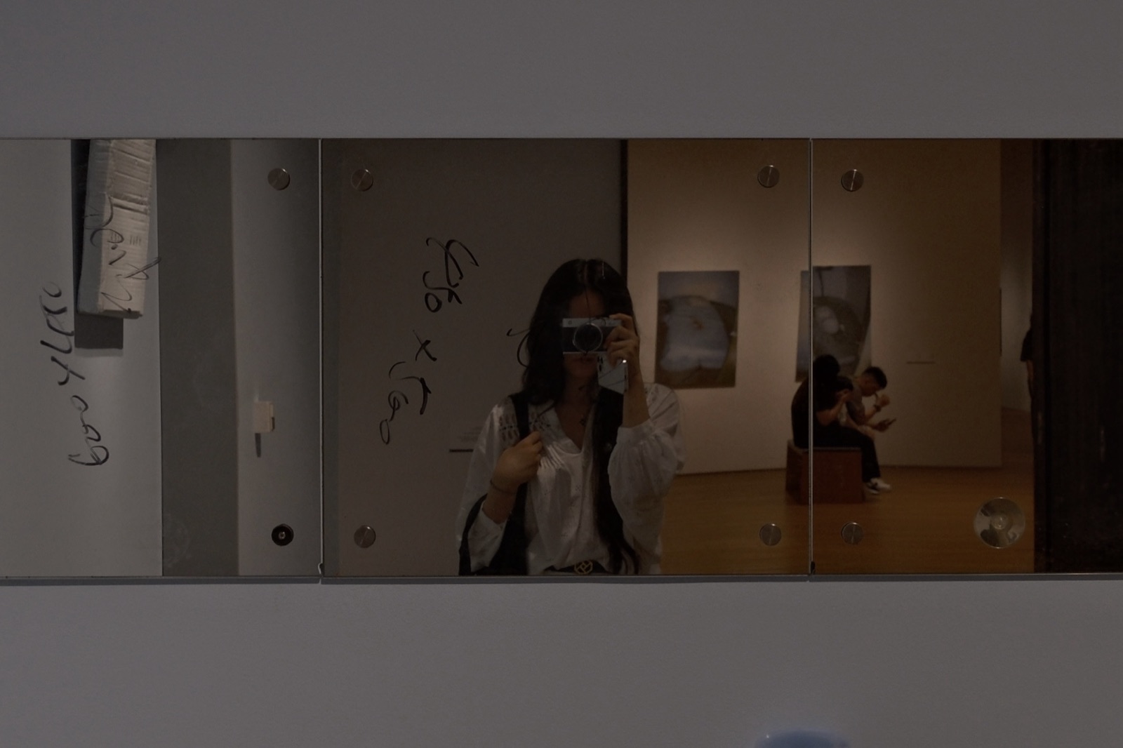 Isabella reflected in a mirrored artwork, camera raised to her eye