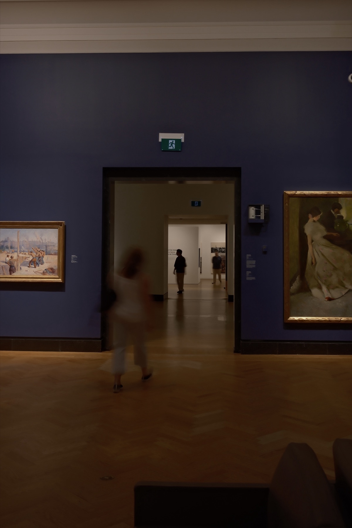 A visitor blurring through the blue European gallery