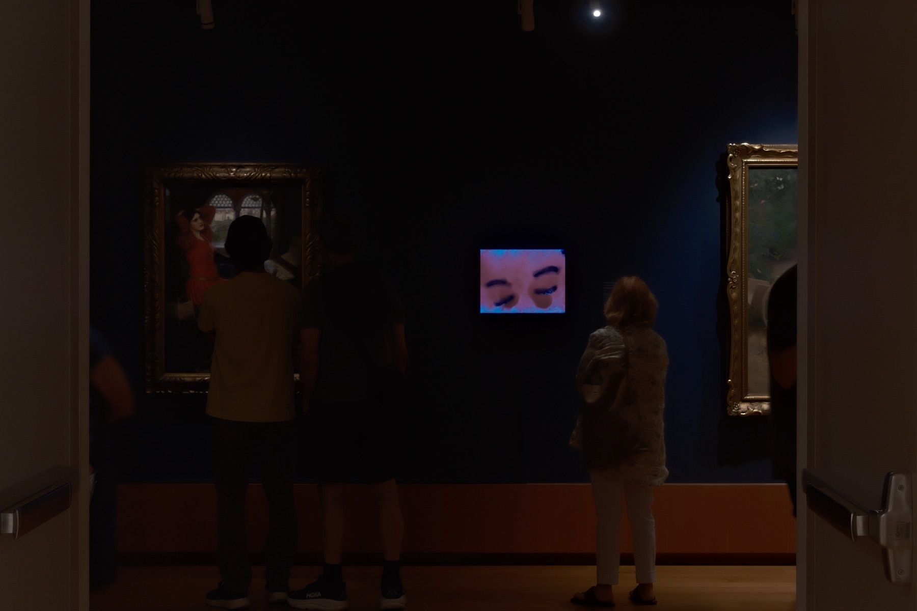 A video of closed eyes glowing on a dark museum wall — With My Eyes Open