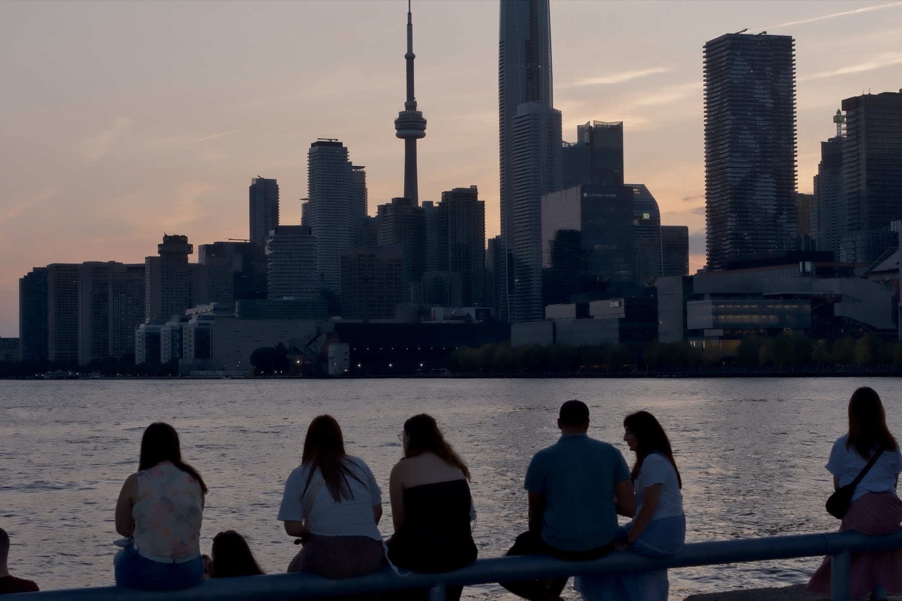 People on the railing facing the skyline and the setting sun