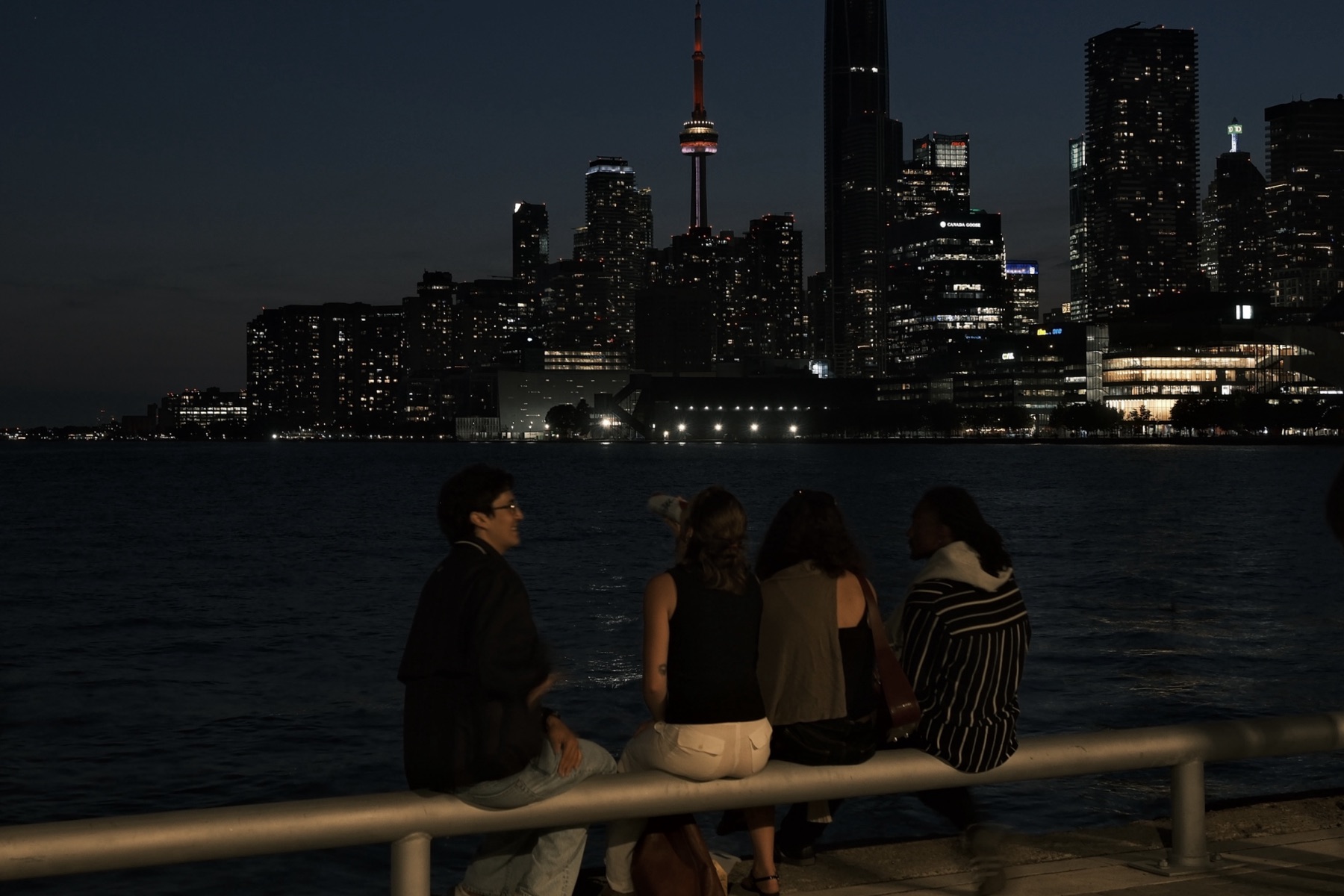 Four friends on the railing at night, the city lit behind them
