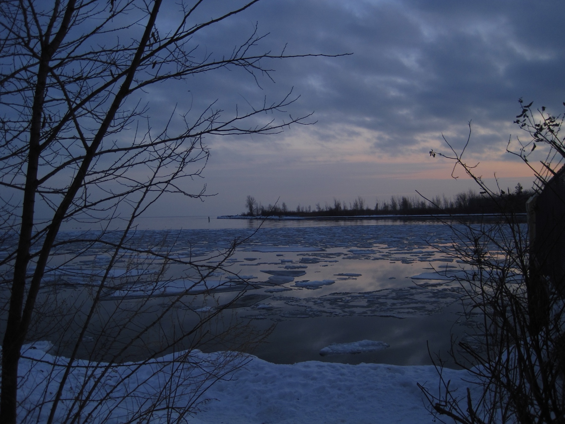 A frozen bay at blue dusk, a thread of pink at the far shore