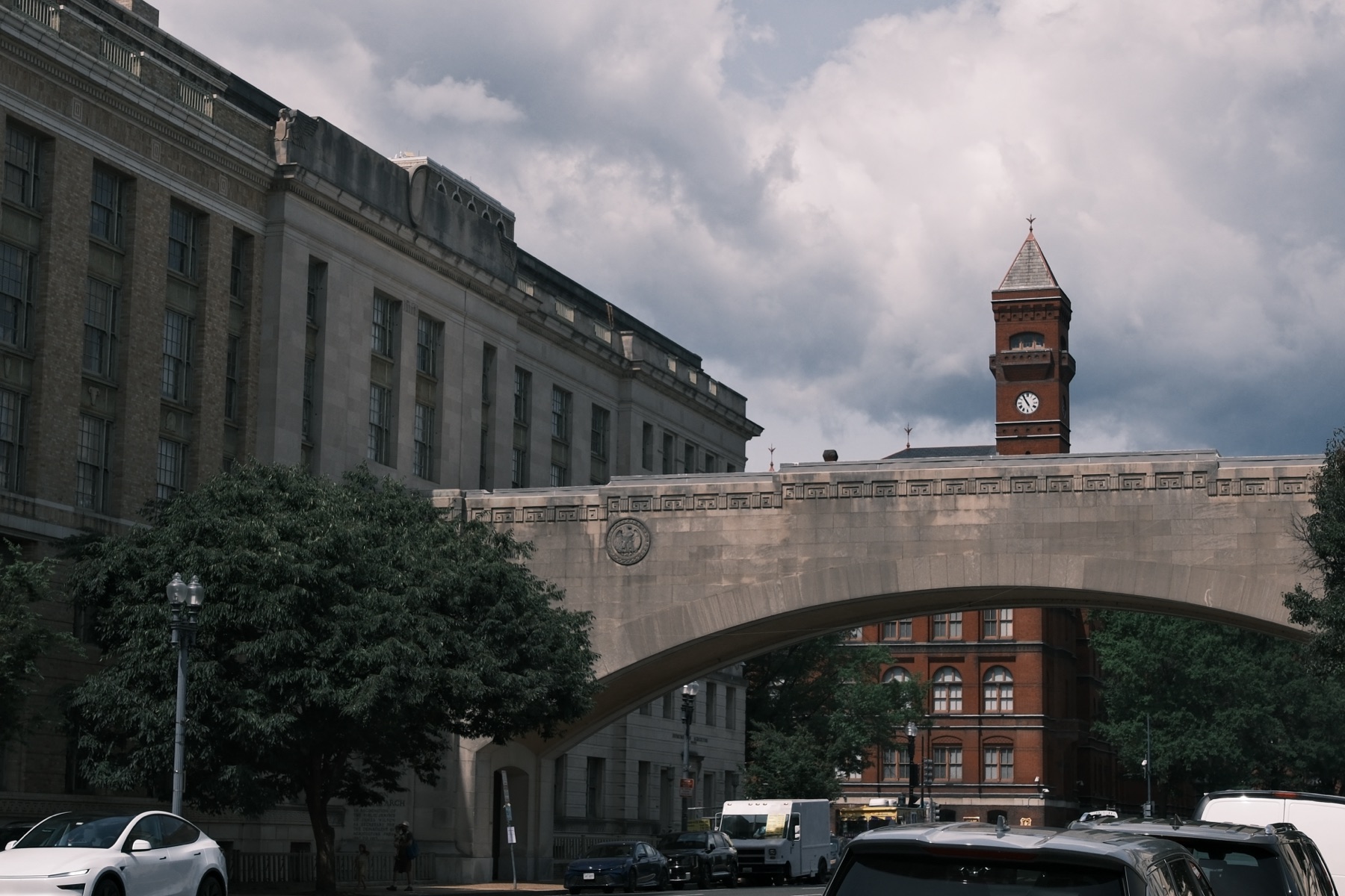 A stone bridge between federal buildings, the clock tower behind