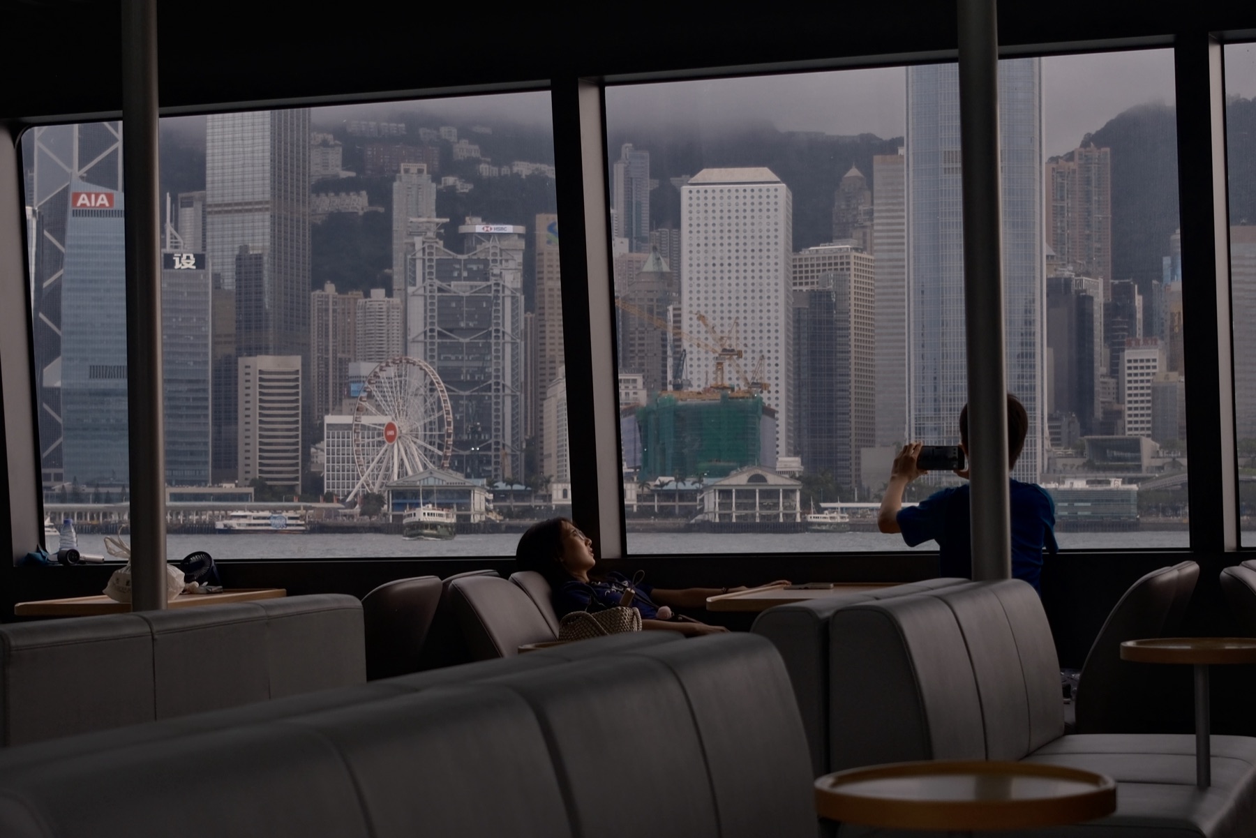 A man photographing the wheel and the banks through the ferry window