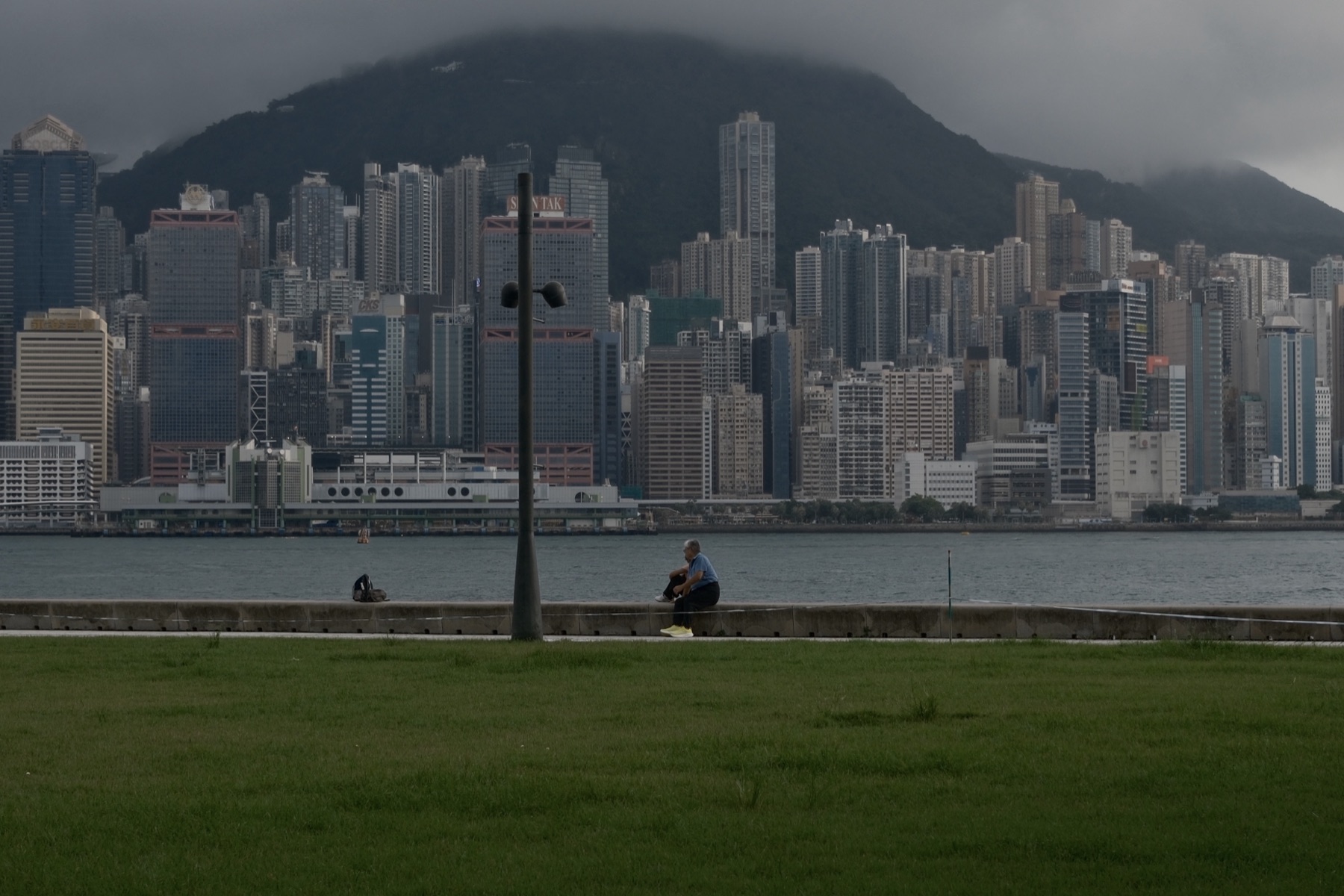 A man sitting on the seawall with the whole skyline to himself