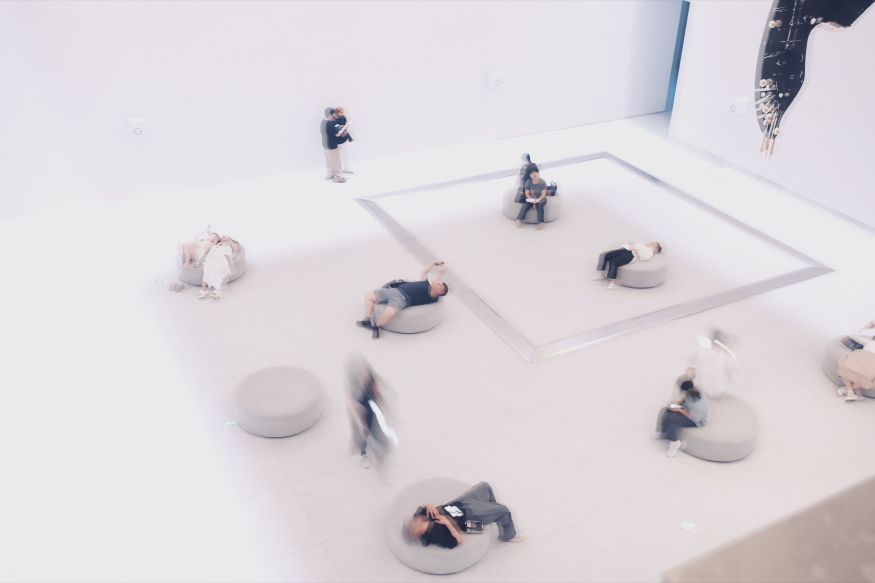 Visitors lying beneath the whale in the white hall, blurred by a one-second exposure
