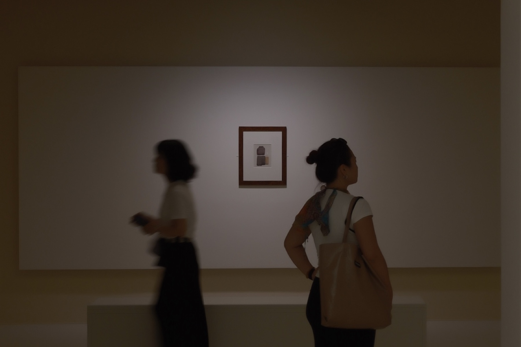 One small Morandi between two visitors, one walking, one still