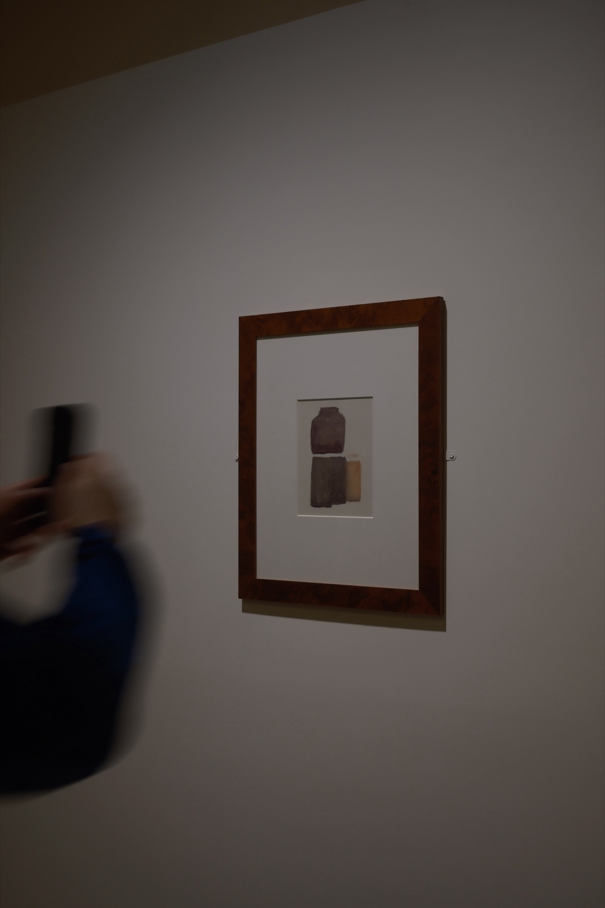 A Morandi watercolour of bottles, a phone raised in a blur beside it