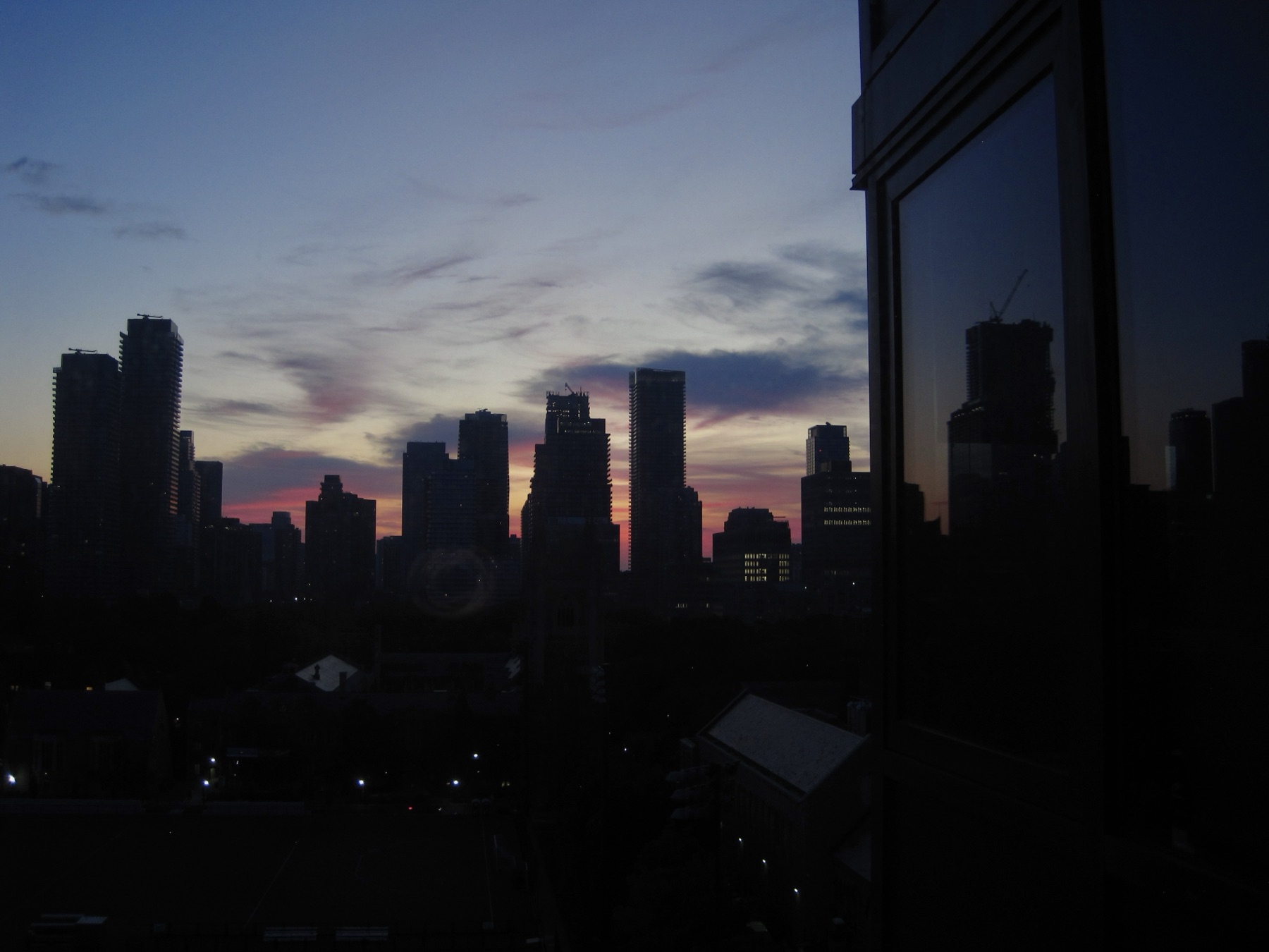 A violet and rose dawn behind the silhouetted skyline