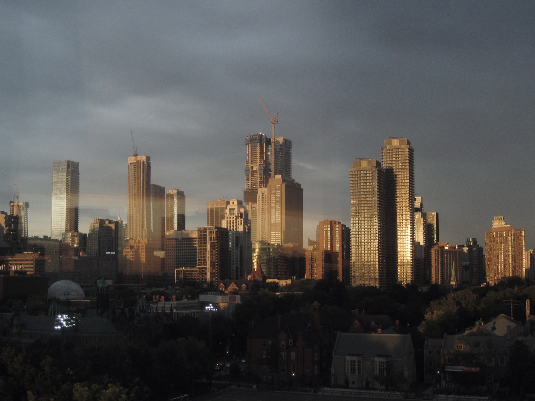 Gold light raking the Toronto skyline under a storm cloud — Same Window, Every Sky