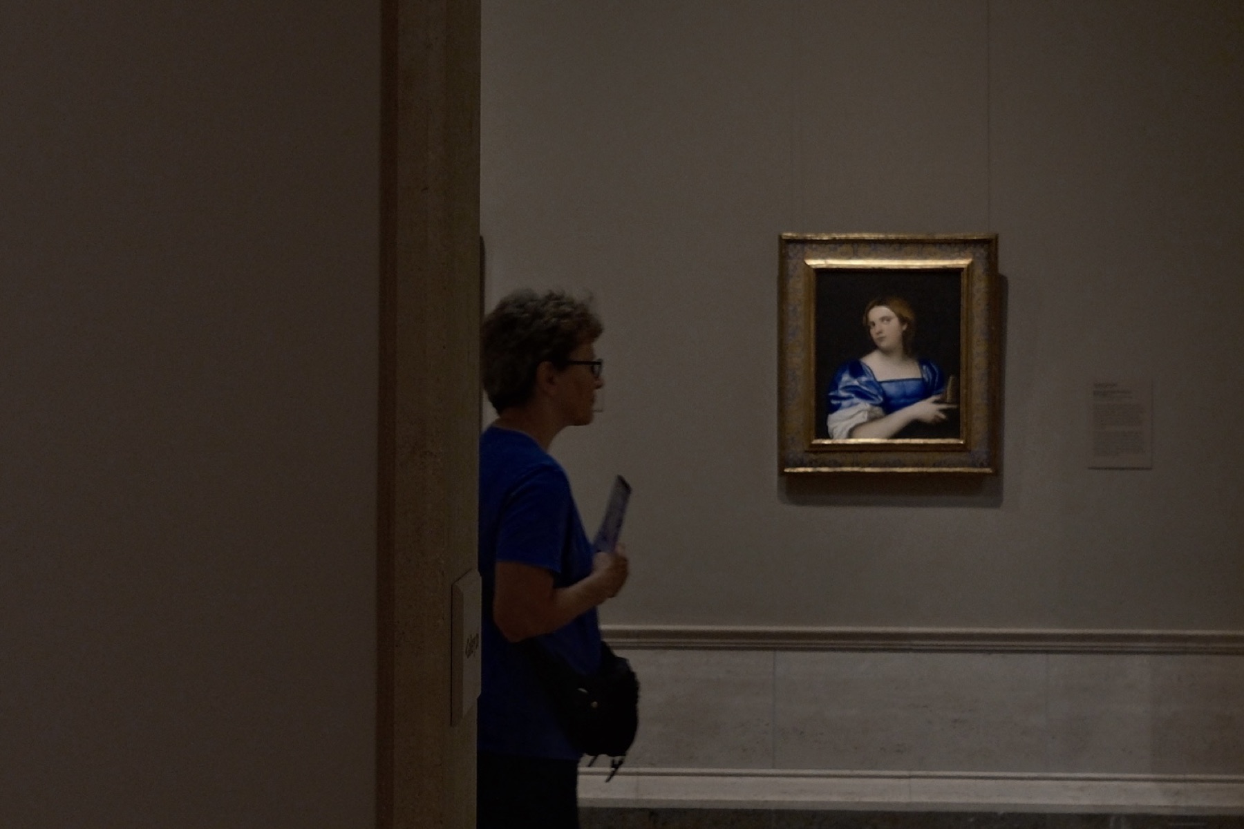 A visitor in blue before a portrait of a lady in blue