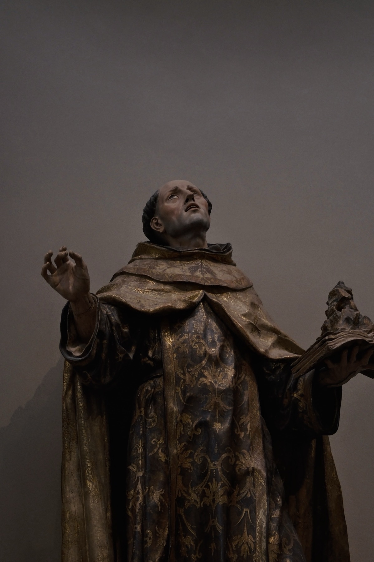 A polychrome wooden saint looking upward