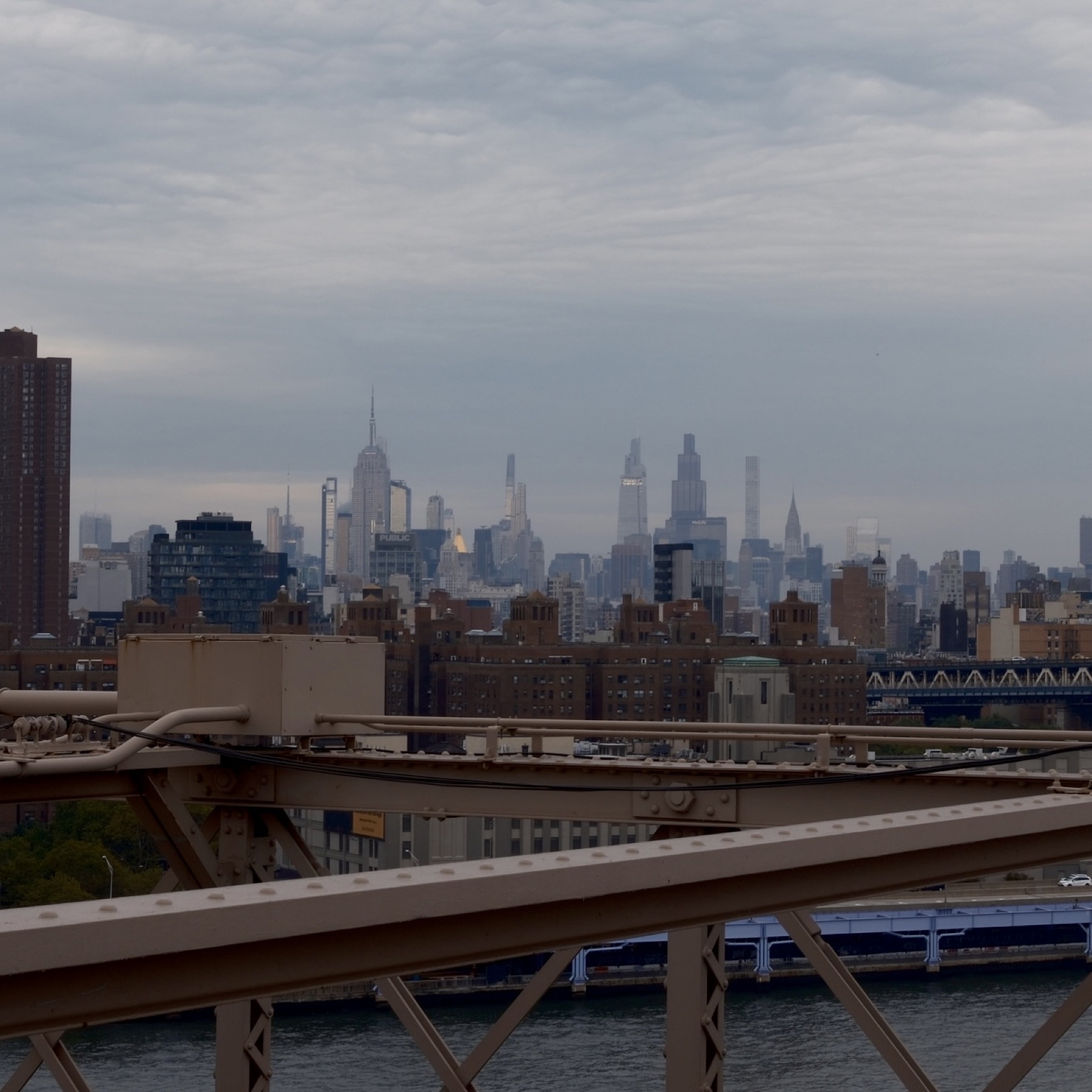 The midtown skyline over rooftops, seen past the bridge's struts