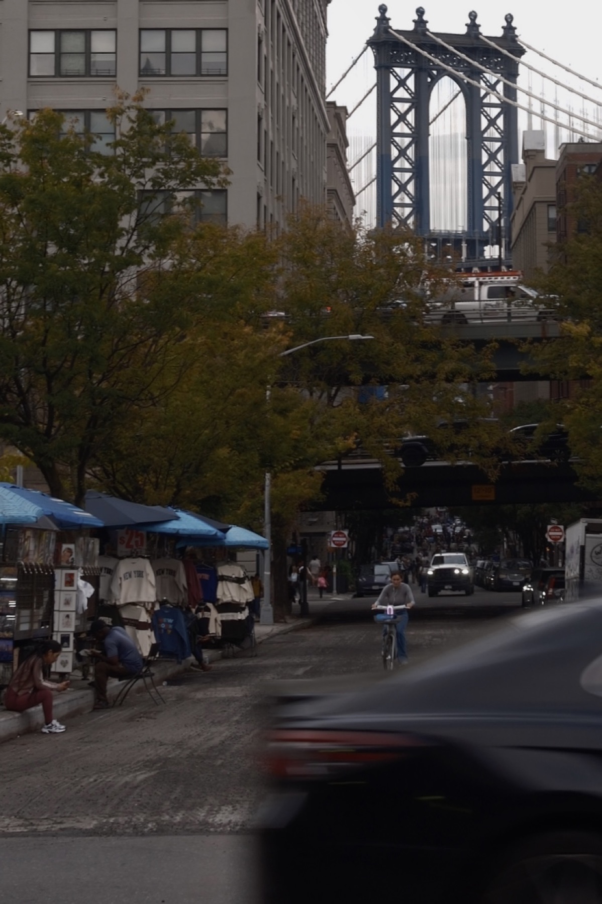 The Manhattan Bridge tower over Dumbo, souvenir stalls under the trees
