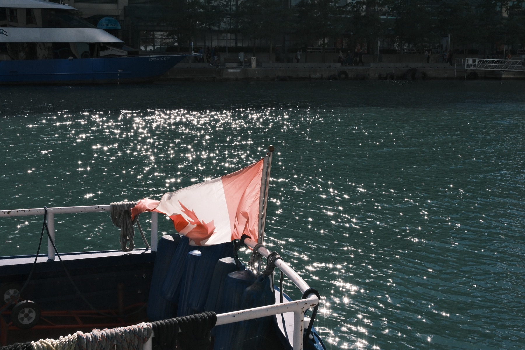 The flag at the stern over glittering water