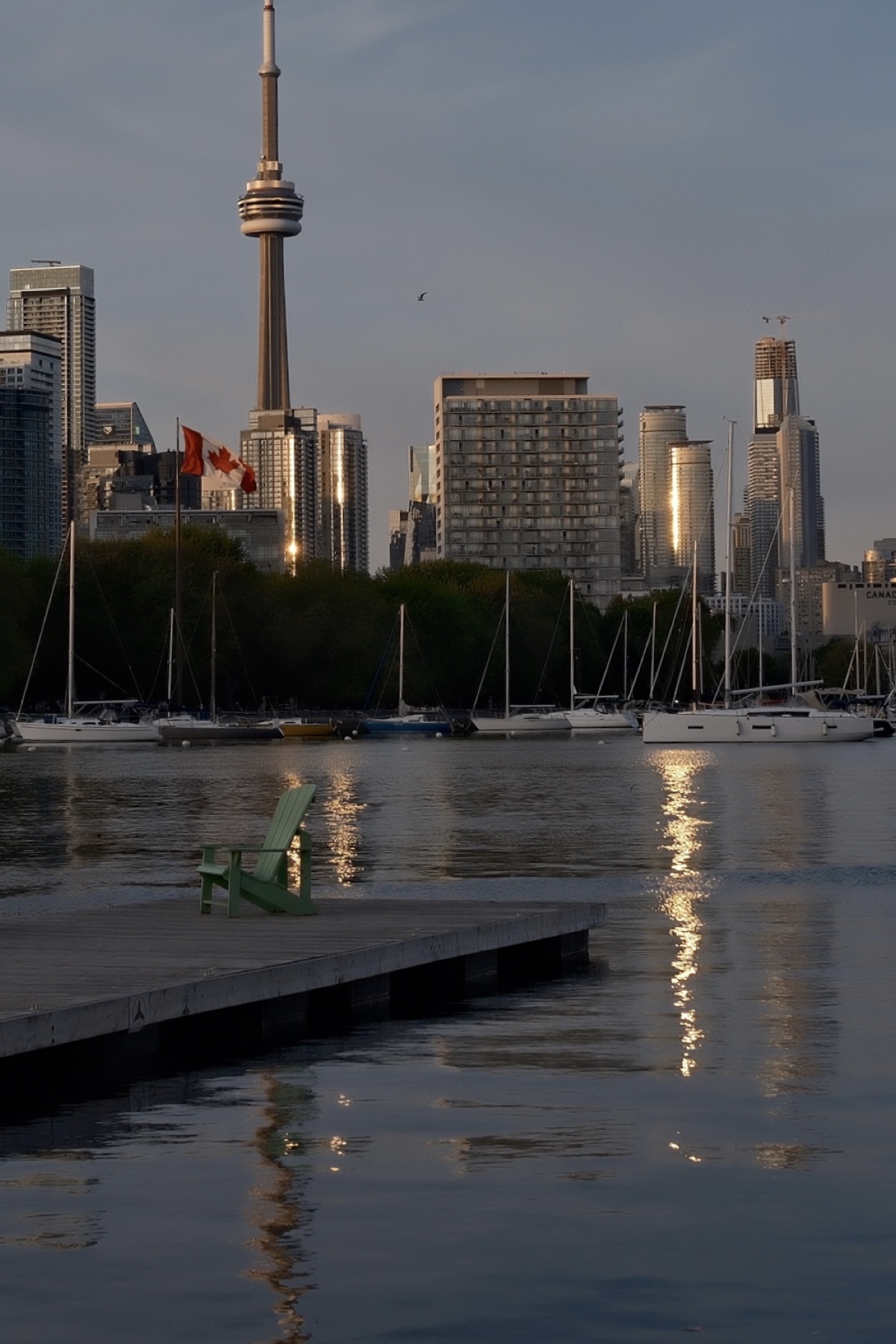 A green Muskoka chair facing the CN Tower skyline