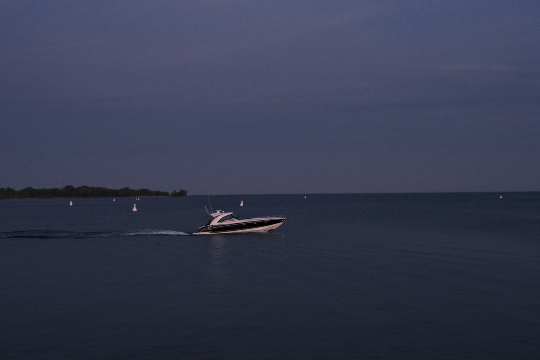 A speedboat trailing a wake across blue-hour water